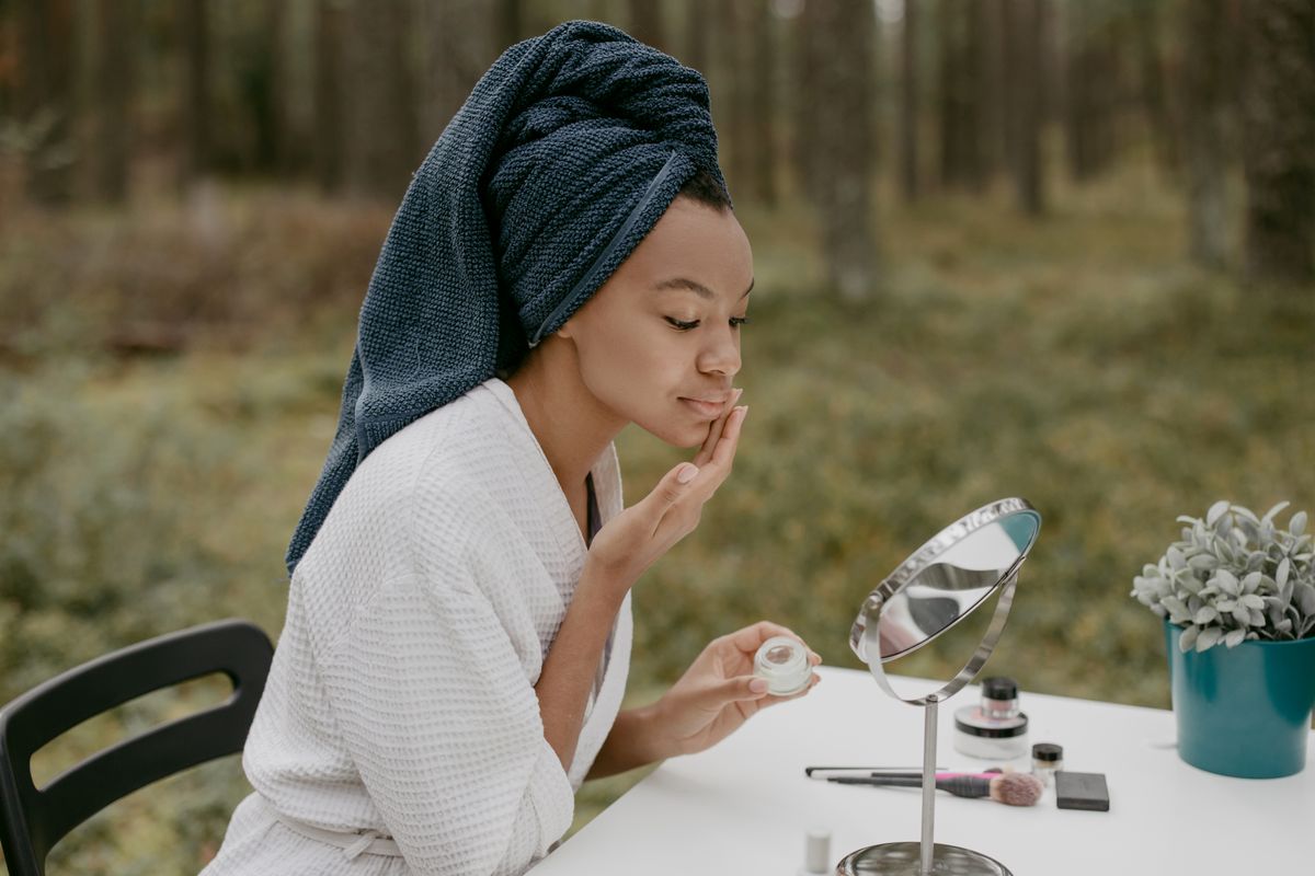 Mujer aplicando crema facial de noche frente al espejo