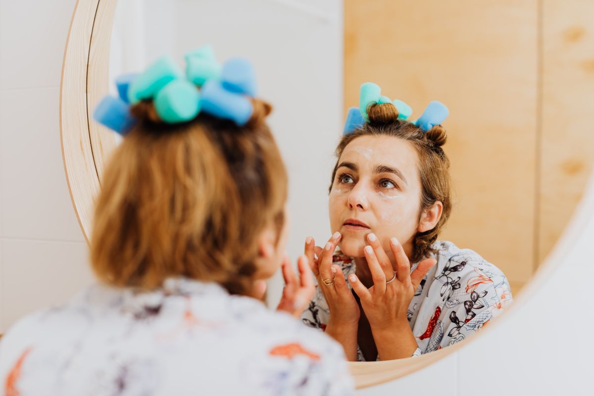 Mujer aplicando crema frente al espejo