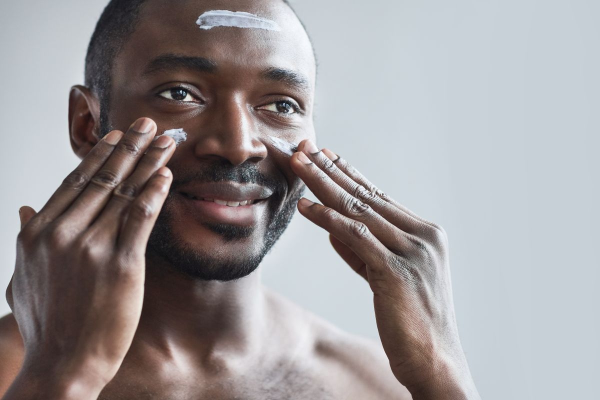 Hombre sonriente aplicando crema facial