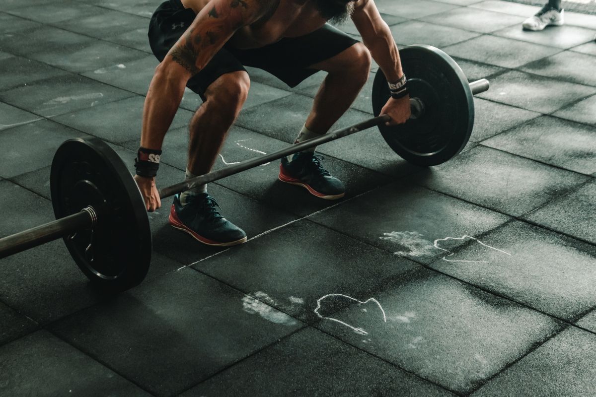 Hombre musculoso levantando barra en el gimnasio